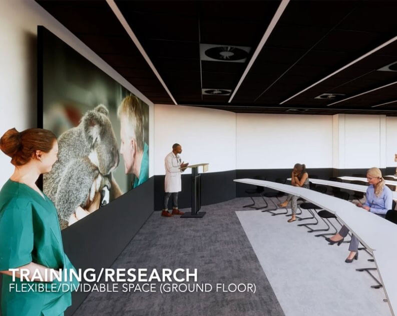 A presenter speaks at a podium in a curved classroom with people seated at desks; a large screen displays an image of a koala. Text reads: TRAINING/RESEARCH FLEXIBLE/DIVIDABLE SPACE (GROUND FLOOR).