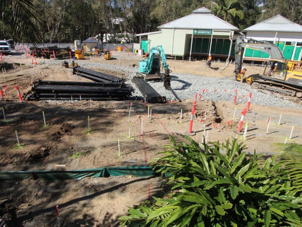 Construction site with a teal excavator digging up ground in front of Currumbin Wildlife Hospital